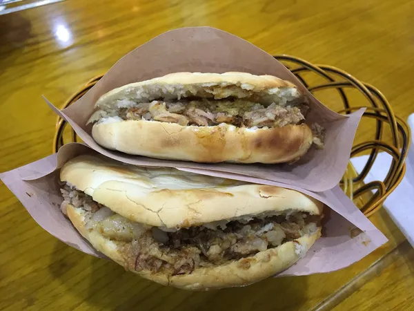 Two roujiamo sandwiches stuffed with chopped braised pork in a basket